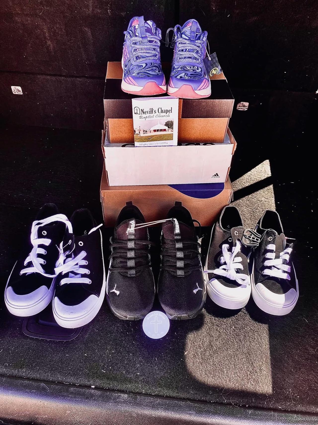 A stack of shoe boxes with new sneakers and a Nevill's Chapel booklet