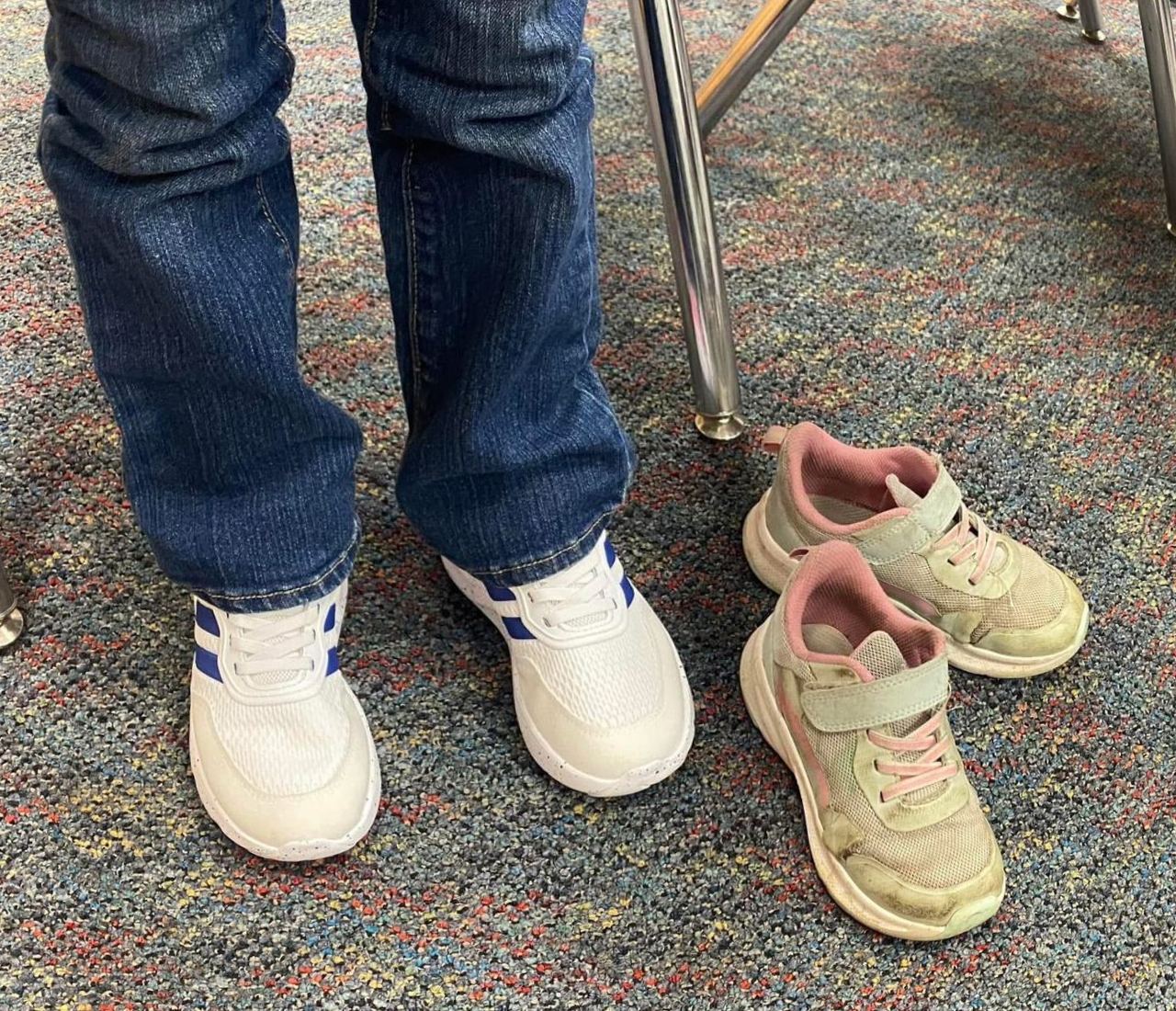 A child wearing brand-new white sneakers, old shoes set aside